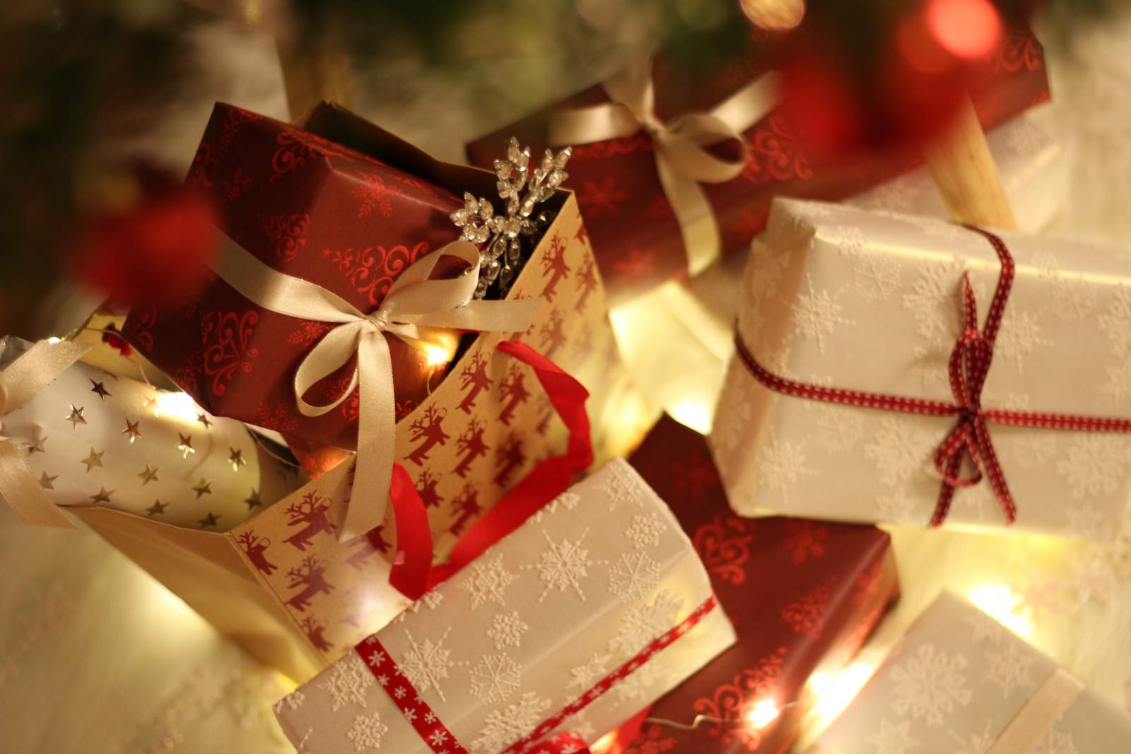 Gifts wrapped up in white and red wrapping paper, inside reindeer-patterned gift bags
