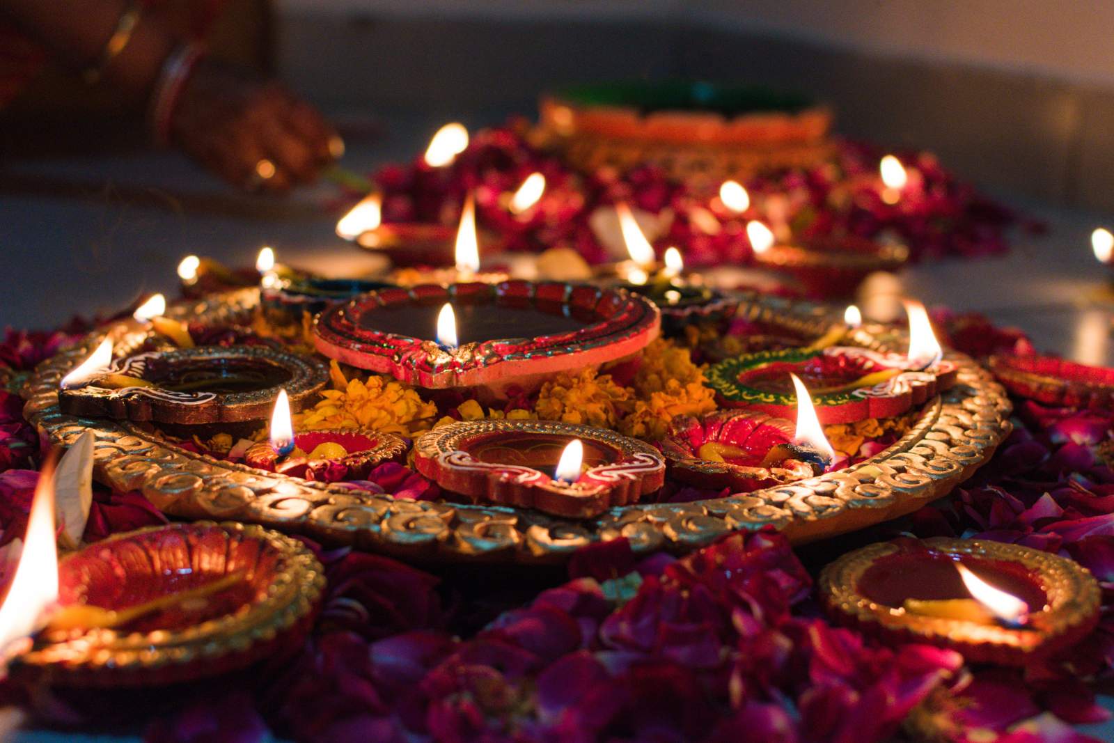Lit candles in the shape of teardrops, arranged in a circle with a hand placing the final one