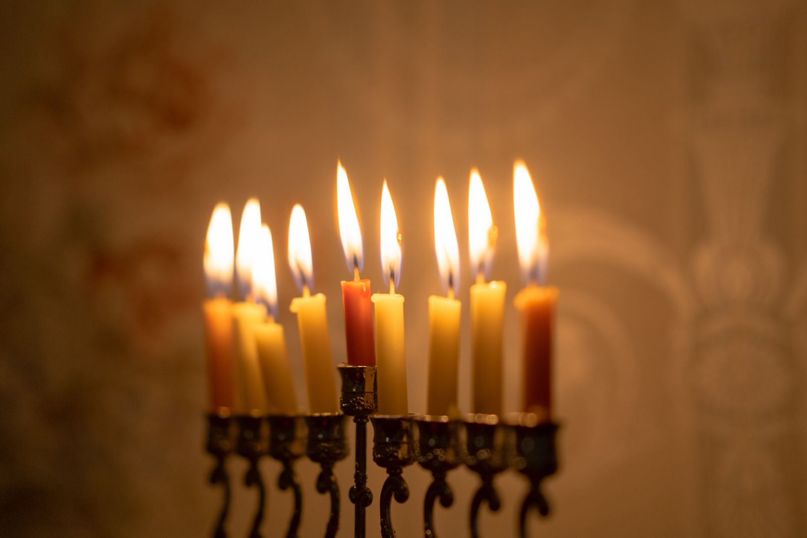 Lit candles in the shape of teardrops, arranged in a circle with a hand placing the final one