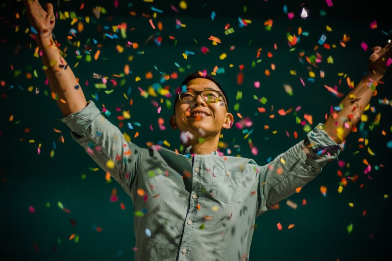 Boy enjoying confetti flying in the sky at night